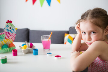 Wall Mural - girl paints Easter eggs at home against background of bright decor. kids craft. create art for children