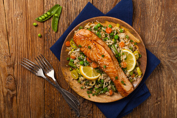 Wall Mural - Asian dish. Fried salmon with rice and vegetables. Sprinkled with sesame seeds.