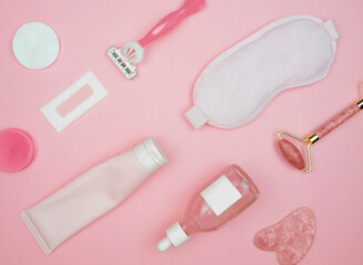 layout of items for face and body care on a pink background, cleansing gel, serum, face roller, guasha, razor, mask, cotton pad, balm, wax strip, pink, flat lay