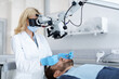 Female stomatologist using dental microscope at modern clinic