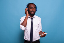 Portrait Of Man Relaxing With Eyes Closed Enjoying Audio Content Streaming From Smartphone To Wireless Headphones. Businessman Listening To Calming Podcast Or Audiobook On Over Ear Headset.