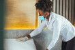 Maid wearing mask cleaning bedroom after guests in hotel room. Hotel service concept. Maid working at a hotel doing room service and disinfecting due to COVID-19 pandemic