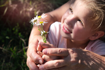 Grandmother and granddaughter hands holding bouquet of wildflowers, close up, love concept