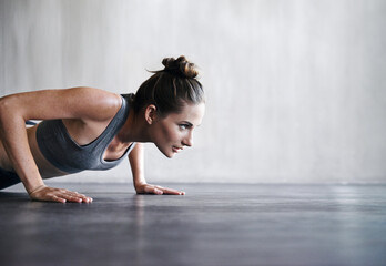 Poster - Pushing the limits. Shot of a woman doing push-ups at the gym.