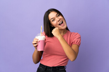 Wall Mural - Teenager girl holding a strawberry milkshake celebrating a victory