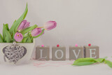 Fototapeta Tulipany - Walentynkowe tło, różowe tulipany w pudełku drewnianym z serduszkiem i napis z brył drewnianych układające się w sowo love.