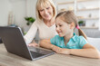 © Prostock-studio - Happy mature woman and granddaughter using laptop