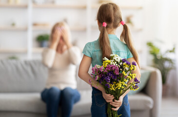 Wall Mural - Back view of little girl greeting woman with flowers