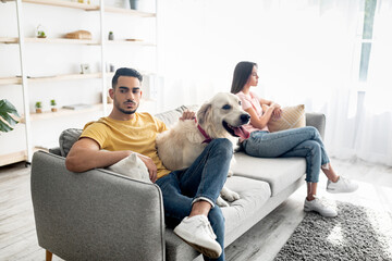 Canvas Print - Upset young Arab man hugging pet dog after conflict with his girlfriend at home