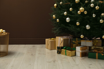 Wall Mural - Beautifully decorated Christmas tree and many gift boxes near brown wall indoors, space for text