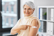 © Syda Productions - medicine, health and vaccination concept - happy smiling vaccinated senior woman showing medical patch on her arm at hospital