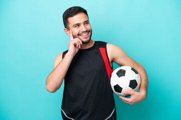 Wall Mural - Young football player Brazilian man isolated on blue background thinking an idea while looking up