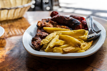 Wall Mural - Sausage, veal and pork meat barbecued and served with french fries