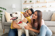 © Prostock-studio - Portrait of happy multiracial couple scratching their pet dog, sitting on floor at home
