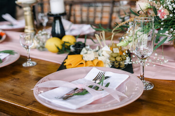 Wall Mural - A beautiful outdoor wedding setting in pink flowers. plates and cutlery on a wooden table against a backdrop of greenery. On a Summer day 
a wooden reception table in the backyard, decorated with rose