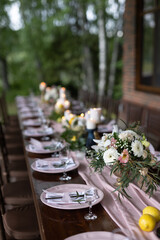 Wall Mural - A beautiful outdoor wedding setting in pink flowers. plates and cutlery on a wooden table against a backdrop of greenery. On a Summer day 
a wooden reception table in the backyard, decorated with rose