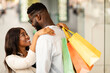 © Prostock-studio - Happy black couple hugging and holding shopping bags