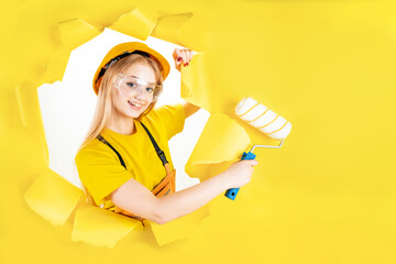 Positive busy female builder involved in renovation and repair of building holds roller and paint brush follows strict safety regulations wears protective equipment has leadership skills. Copy space.