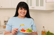 © New Africa - Happy overweight woman eating salad in kitchen. Healthy diet