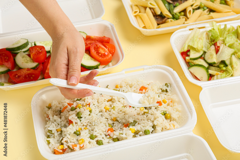 Woman taking food from container on color background, closeup
