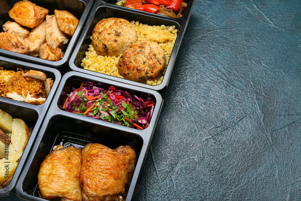Food delivery containers with different delicious meals on dark background, closeup