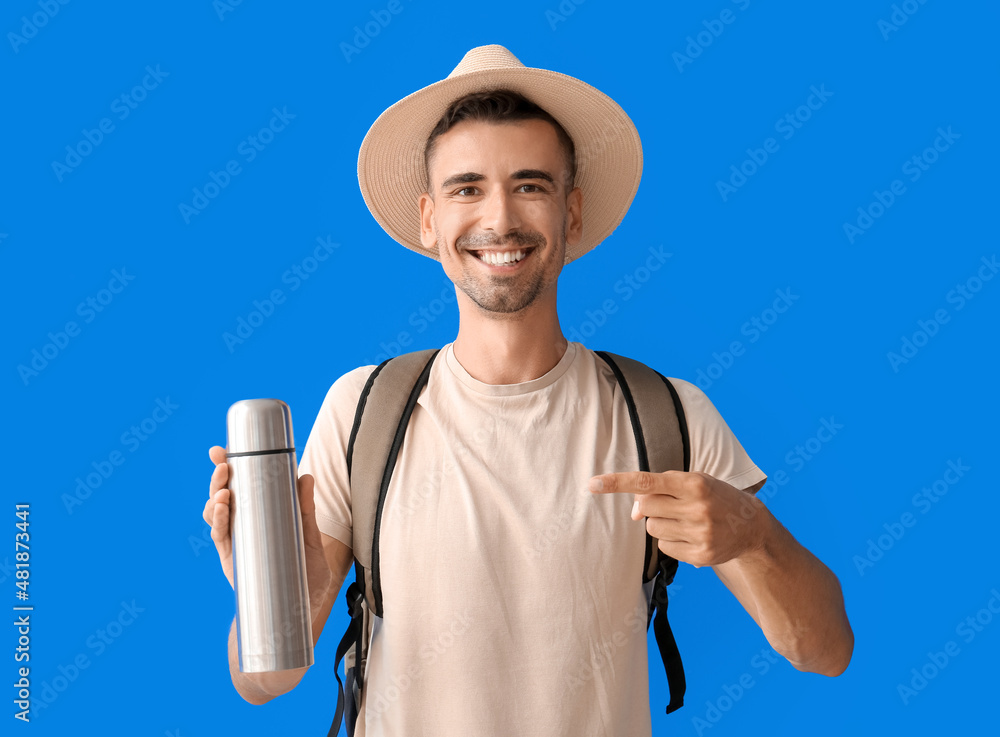 Male tourist with thermos on color background