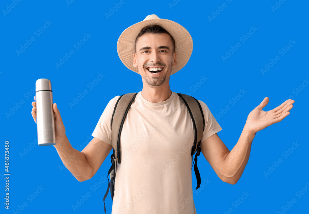 Male tourist with thermos on color background