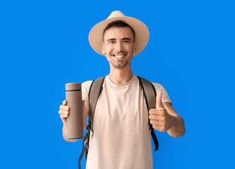 Sticker - Male tourist with thermos showing thumb-up on color background