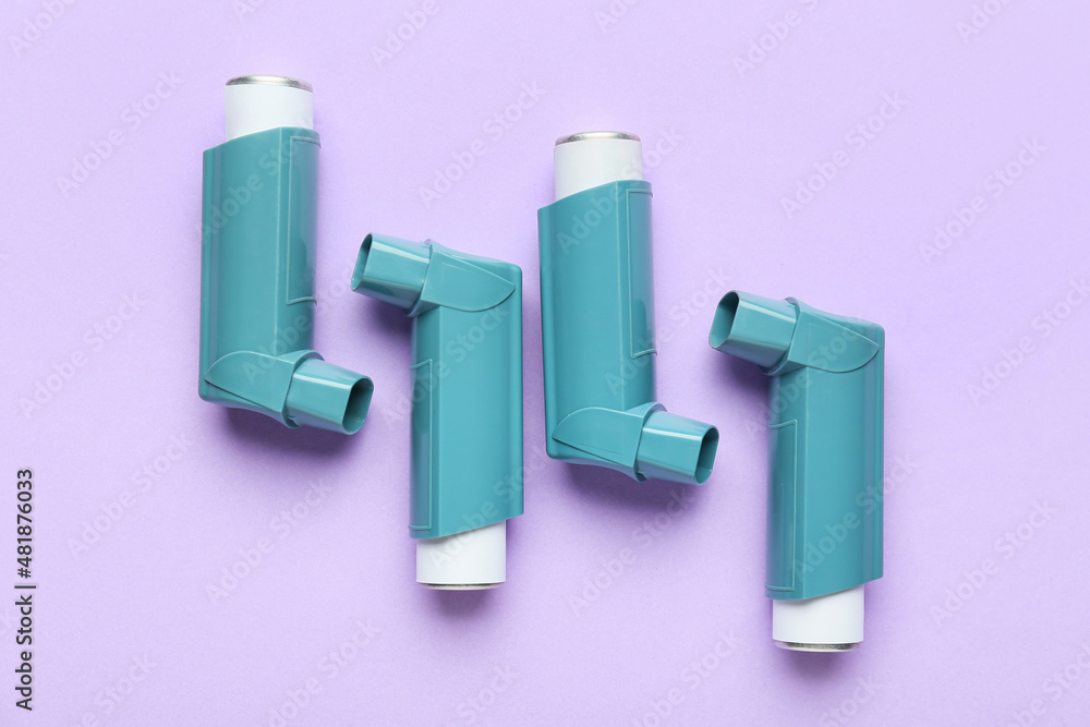 Modern asthma inhalers on color background