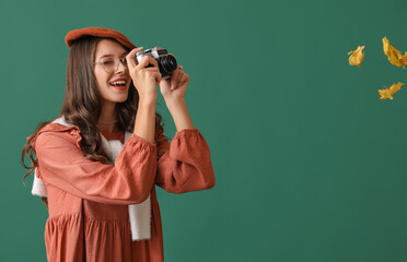 Wall Mural - Beautiful Parisian woman taking pictures of autumn leaves on green background