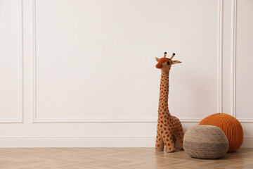 Wall Mural - Toy giraffe and poufs near white wall indoors, space for text. Interior design