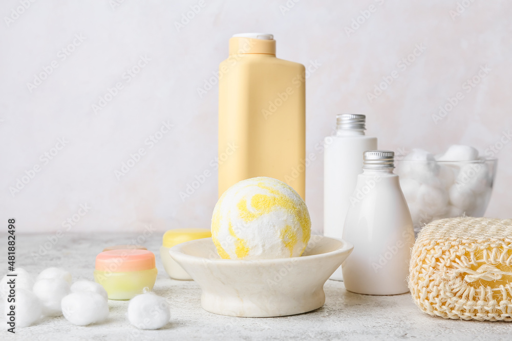 Bowl with bath bomb and supplies on light background