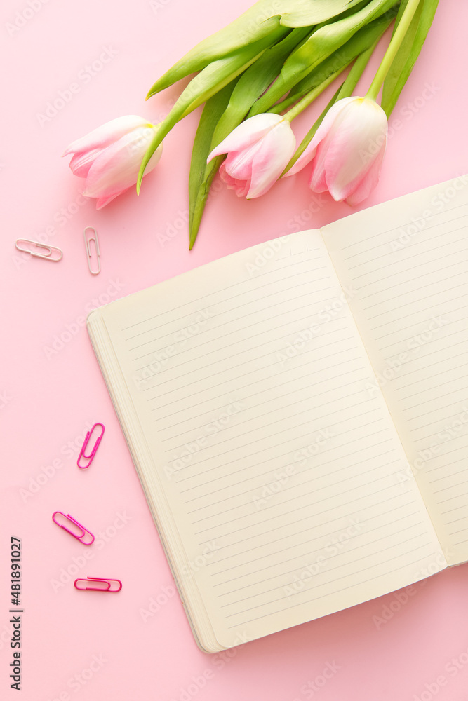 Blank notebook, clips and tulips on pink background