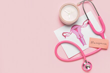 Papers With Word MENOPAUSE, Uterus, Stethoscope And Alarm Clock On Pink Background