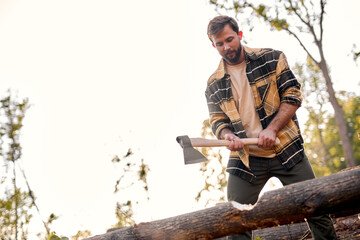 Sticker - Bearded experienced lumberjack working in forest chopping trees, getting firewood, using sharp ax. Man holding an industrial ax tool. strong powerful caucasian lumberjack preparing firewood.