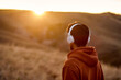 © Roman - Rear View On Unrecognizable Sportsman In Headphones Looking At Side At Sunrise, Motivated To Be Healthy In Perfect Physical Shape, Fitness Concept. View From Back. In Mountains