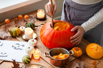 Woman carves a pumpkin for handmade Jack-O-lantern at home for Halloween party decoration. Concept of holiday seasonal handmade decor. Autumn colors, faceless, close-up