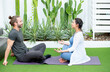 © narong - Caucasian man sit in front of pregnant wife who exercise and relax with yoga in garden of their house.