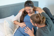 © narong - Man hug pregnant woman and stay on bed together and they look to belly with happiness emotion. Concept of good activity together of parent at home.