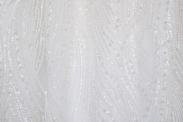  Close up shot at the white luxury gown textile dress with the glitter pattern detail that using with women bride. fashion and clothing background concept.