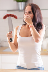 Wall Mural - Woman resist grilled sausage on top of knife in her hand