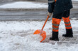 © Pokoman - Removing snow from the sidewalk after snowstorm. A road worker with a shovel in his hands and in special clothes cleans the sidewalk and the road from snow. Snowstorm and hurricane in the city.