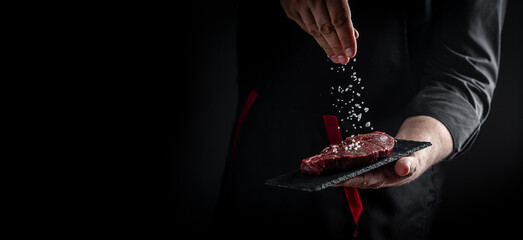 Chef hands cooking meat steak and adding seasoning in a freeze motion. Fresh raw Prime Black Angus beef rump steak. banner, menu recipe