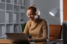 Young Woman With Laptop Listening To Music At Home In Evening