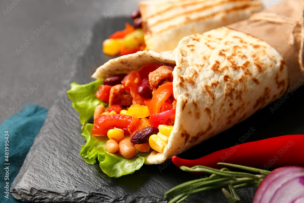 Slate plate with delicious burrito on table, closeup
