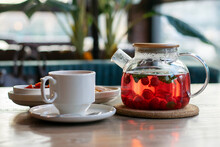 Raspberry Tea With Mint In A Transparent Teapot On A Table In A Cafe.