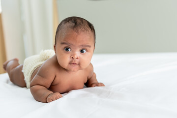african baby black skin newborn is 3 month old, lying on white bed in a bedroom, to african family a