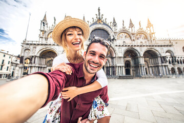 Wall Mural - Beautiful young couple having fun visiting Venice - Tourists enjoying holiday in Italy taking selfie in front of famous landmark - Vacation and happy lifestyle concept