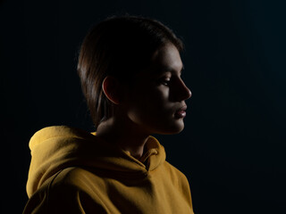 Canvas Print - Relaxation and meditation, a young brunette woman, side view, light silhouette on a dark studio background. Calm face, the importance of mindfulness for young people