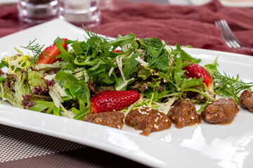 Wall Mural - Salad with chicken liver and strawberry on a white plate
